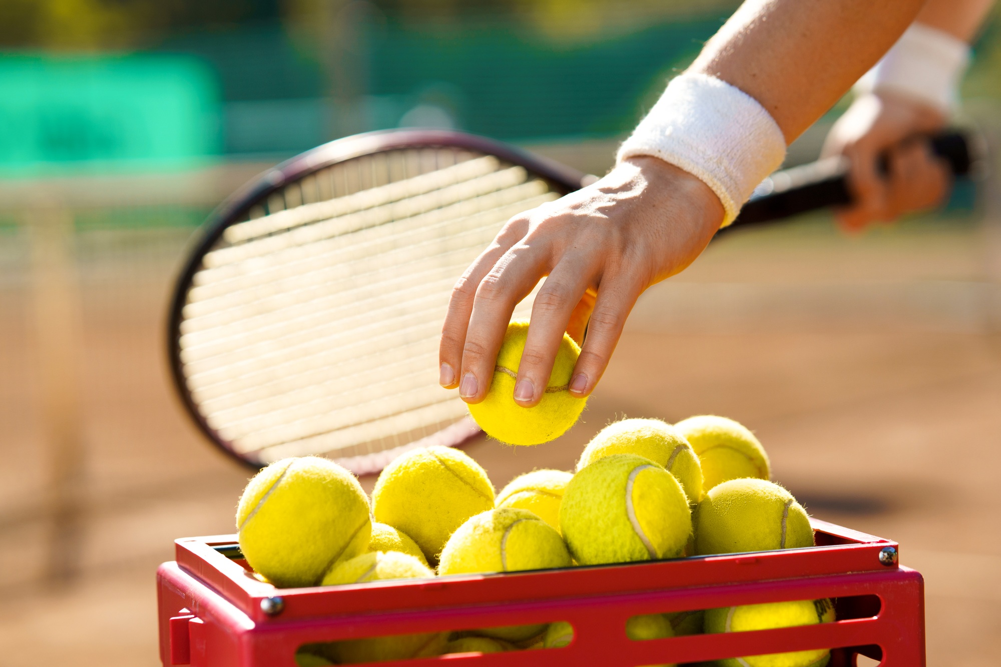 Tennis player at the court takes a ball from a basket