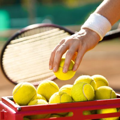 Tennis player at the court takes a ball from a basket